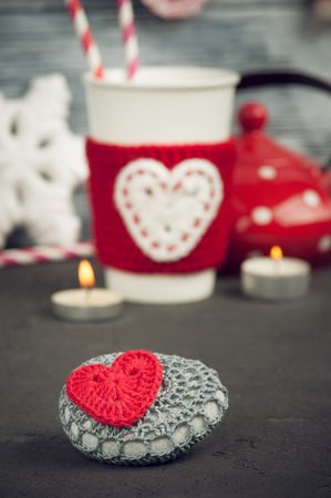 Christmas decoration crochet stone with red heart. Mug, teapot over rustic wooden backgroundの写真素材