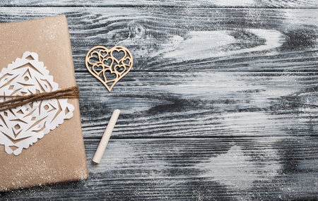 Flat lay background with christmas gift, heart and chalk on wooden background. Craft wrapping. View from aboveの写真素材