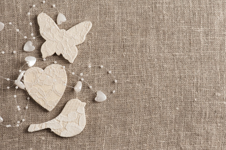 Linen background with wedding decoration. White butterfly, heart, bird. Wedding, xmas rough texture flat layの写真素材