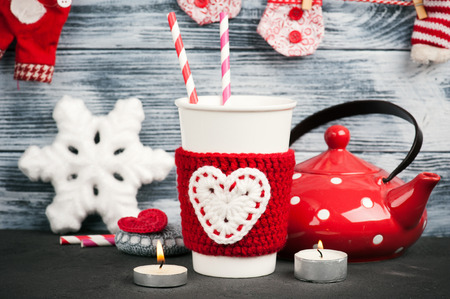 Christmas decoration crochet stone with red heart. Mug, teapot over rustic wooden backgroundの写真素材
