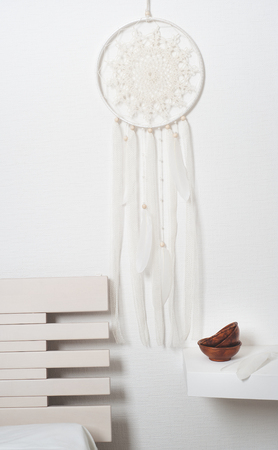 Dream catcher with white feathers in the interior with brown bowlsの写真素材