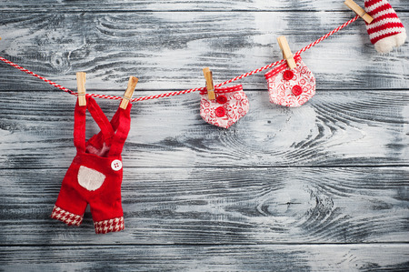 Christmas red garland with doll garments, hanging on rope in front of blue wooden background. Space for textの写真素材
