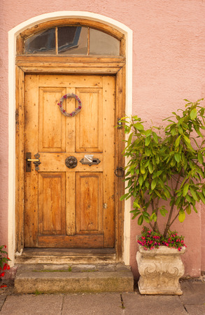 Old door with flowers and tree in vintage tone. Pink wall and weathered stonesの写真素材