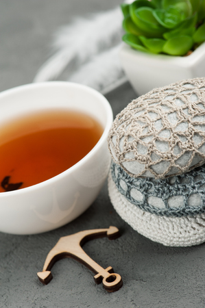 Cup of black tea and crocheted pebbles closeup on concrete background. Shallow focus, toned imageの写真素材