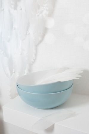 Dream catcher with white feathers in the interior with blue bowls. Toned image and bokehの写真素材