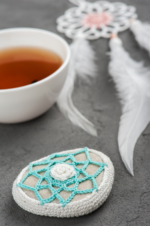 Cup of tea and crocheted pebble closeup on concrete background. Shallow focusの写真素材