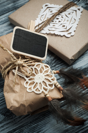 Flat lay background with christmas gift, dream catcher, twine on wooden background. Craft wrapping. Blackboard for chalkの写真素材