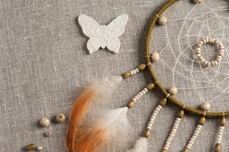 Bright orange green dream catcher closeup. Linen background and feathersの写真素材