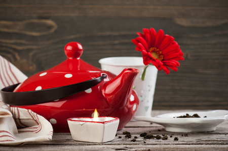 Polka dot red tea pot, tea leaves, candle and flower on the weathered wood table. Tea time conceptの写真素材