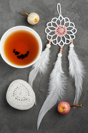 Cup of tea, dream catcher and crocheted pebble closeup on concrete background. Flat lay compositionの写真素材