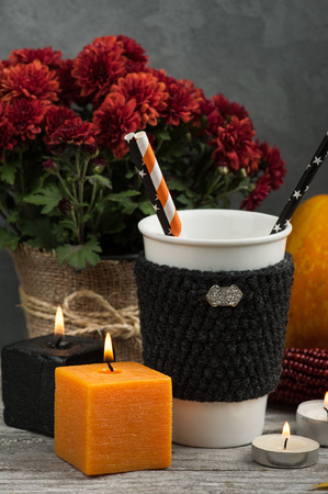 Orange and black lit candles, mug, pumpkin and autumn home decor with rustic wood backgroundの写真素材