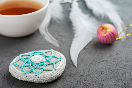 Cup of tea and crocheted pebble closeup on concrete background. Shallow focusの写真素材