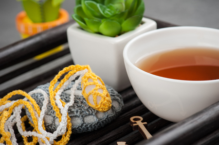Cup of black tea and crocheted pebbles closeup on concrete background. Zen and mindfulness conceptの写真素材
