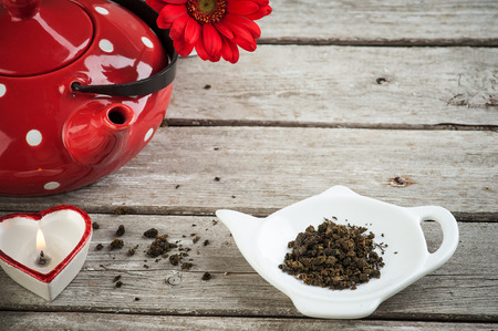 Polka dot red tea pot, tea leaves, candle and flower on the weathered wood table. Tea time conceptの写真素材