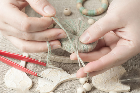 Closeup of female hands holding thread. Handmade workshop composition of beads, threads, tools for DIYの写真素材