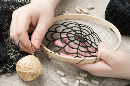 Closeup of female hands holding thread. Handmade workshop composition of beads, threads, tools for DIYの写真素材
