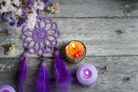 Purple dream catcher on old wooden background with lit candles and dry flowers. Zen decor still lifeの写真素材