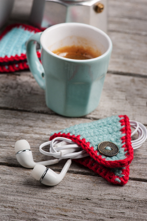Cute knitted earpods holder on wooden table. Life style set with cup of coffeeの写真素材