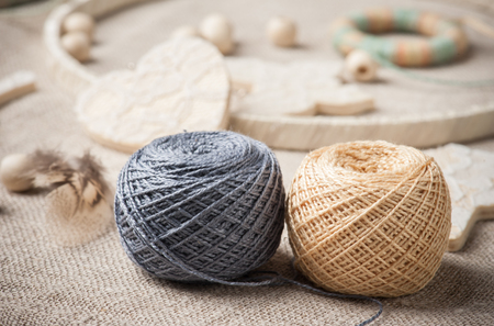 Close-up of grey and beige threads with dream catcher on background. Handmade workshop composition of feathers, beads, tools for DIYの写真素材