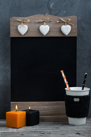 Blackboard menu with lit candles, pumpkin and autumn home decor on rustic wooden background. Place for text. Thanksgiving decorの写真素材