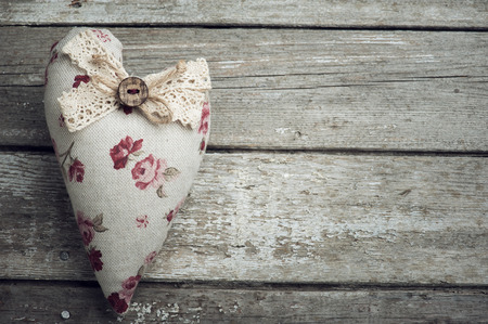 Textile heart with button on old rustic wooden background. Space for textの写真素材