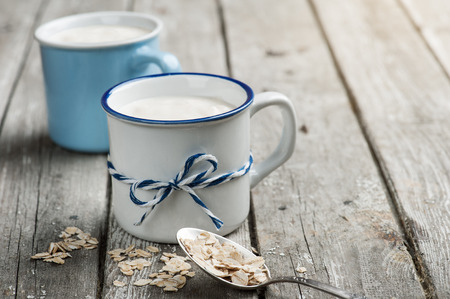 Muesli yogurt with oatmeal on old wooden background. Healthy morning meal in rustic cups. Space for textの写真素材