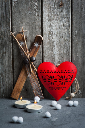 Christmas decoration and lit candles on wooden background. Xmas composition with ski and red heartの写真素材
