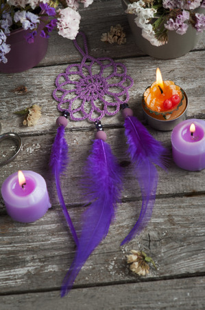 Purple dream catcher on old wooden background with lit candles and dry flowers. Zen decor still lifeの写真素材