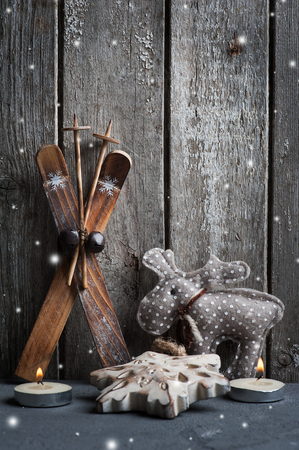 Christmas decoration and lit candles on wooden background. Xmas composition with ski and wood snowflakeの写真素材