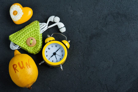 Good morning flat lay with yellow alam clock, lemon, decorative heart and green cord holder for ear phones. Top view with copy spaceの写真素材