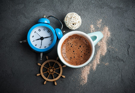 Breakfast concept, mug of hot chocolate or cocoa, alarm clock on concrete backgroundの写真素材