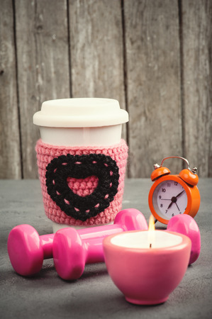 Fitness concept with dumbbells, water mug and alarm clock on woden background. Vintage toned imageの写真素材