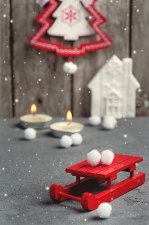 Christmas decoration hanging over wooden background. Xmas composition with red sledge and lit candlesの写真素材