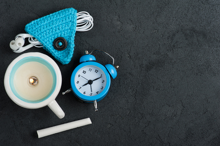 Good morning flat lay with blue alam clock, lit candle, chalk and cord holder for ear phones. Top view with copy spaceの写真素材