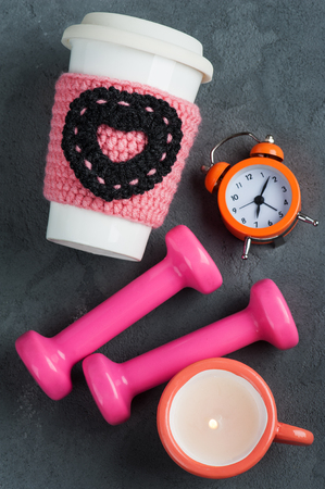 Fitness concept with dumbbells, water mug and alarm clock on woden background. Vintage toned imageの写真素材