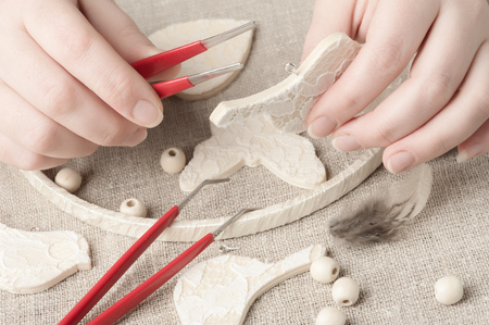 Closeup of female hands holding tool for DIY. Handmade workshop composition of beads, threads, toolsの写真素材