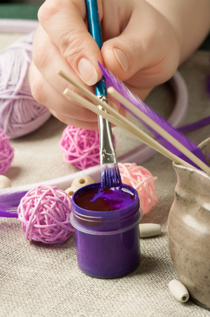 Closeup of female hands painting wooden beads, having dream catcher assembled. Handmade workshop composition of feathers, beads, tools for DIYの写真素材