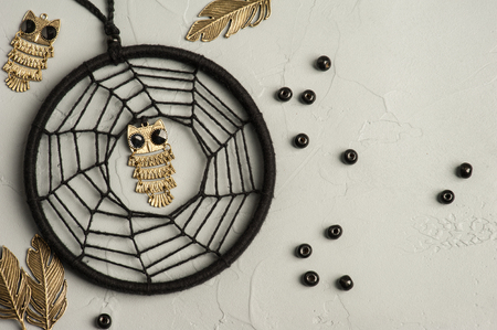 Black dream catcher on concrete background with metal owls and beads. Hallowen decor still lifeの写真素材