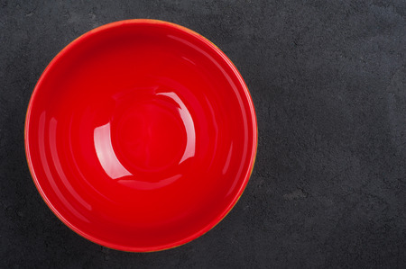 Black concrete background with empty red plate, top view, copy space.の写真素材