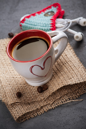 Cute blue knitted ear pods cord holder and espresso on wooden table. Life style set with cup of coffeeの写真素材