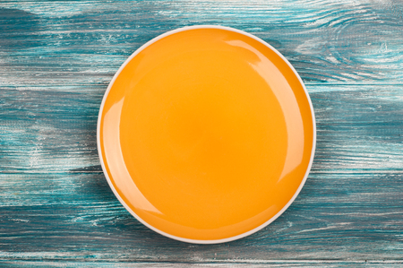Empty yellow plate over blue wooden table background. View from above with copy spaceの写真素材