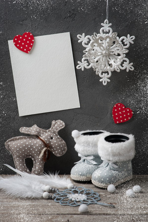 White empty card on concrete wall with burning candle and christmas decorations. Space for greeting text.の写真素材