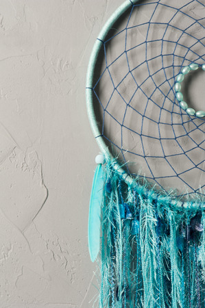 Dream catcher with blue threads and bead in the interior. Closeup with concrete wallの写真素材