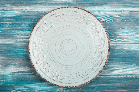 Empty rustic plate over blue wooden table background. View from above with copy spaceの写真素材