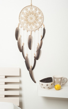 Beige brown dream catcher with feathers on white wall. Copyspace for textの写真素材