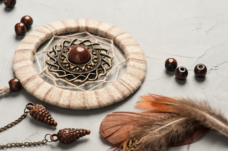 Dream catcher feathers and beads on grey concrete background. Flat lay with copyspaceの写真素材