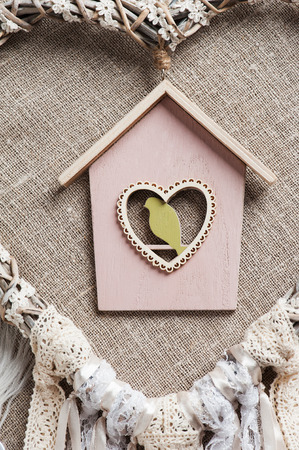 Closeup of pink wooden birdhouse. White beige lace heart shaped dream catcher with pearls. Wedding or Easter decor backgroundの写真素材