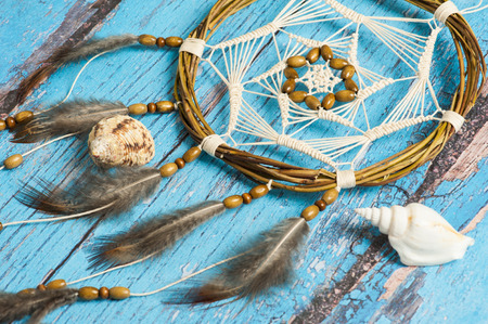 Dream catcher with feathers on blue shabby wooden background. Nautical decor with shellsの写真素材