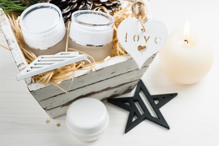 Beauty products and cosmetics with Christmas decoration and lit candle composition in shabby white wooden basketの写真素材