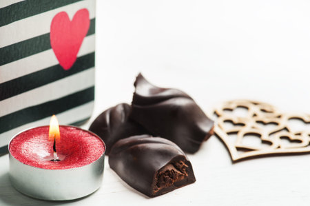 Red sparkling lit candle and dark chocolate composition for Valentine's Day.